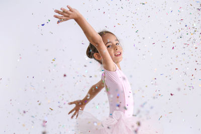 Portrait of cute girl dancing with multi colored confetti