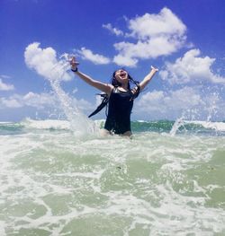 Low angle view of cheerful girl enjoying in sea against sky