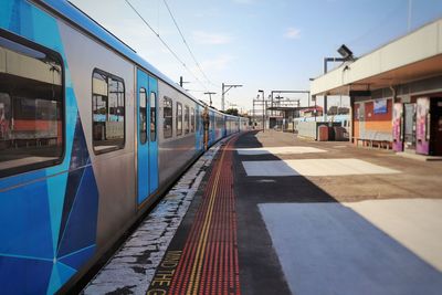 Train at railroad station in city against sky