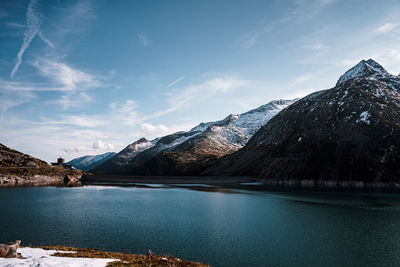 Scenic view of lake by snowcapped mountains against sky