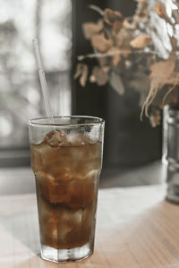 Refreshing cocktail with a straw on the table by the window in the cafe.