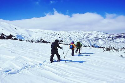 People on snowcapped mountain against sky