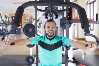 Portrait of cheerful athlete exercising in gym