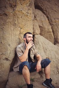 Full length of young man sitting on rock