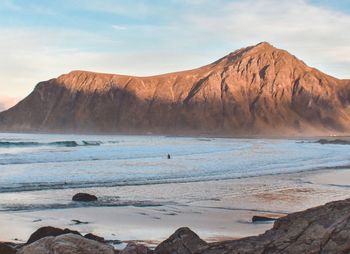 Scenic view of sea by mountains against sky