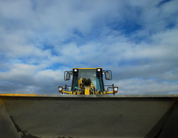 Low angle view of man sitting at commercial dock against sky