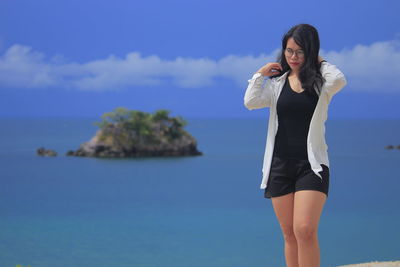 Young woman standing in sea against sky