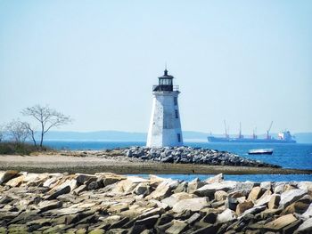 Lighthouse by sea against sky