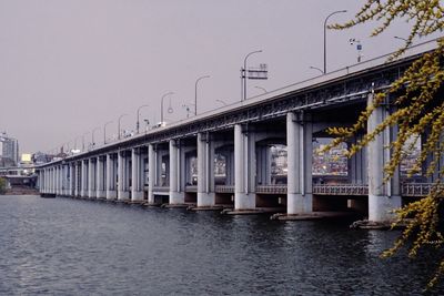 Bridge over river against sky in city