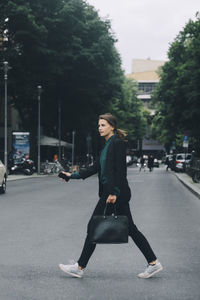 Side view of businesswoman crossing street in city