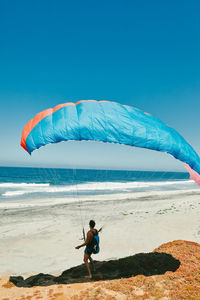 Young man paragliding on beach of paciifc coast in baja, mexico.