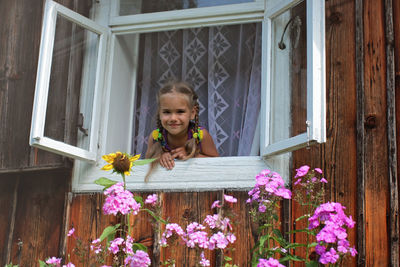 Portrait of young woman standing by window