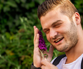 Close-up portrait of young man holding purple outdoors