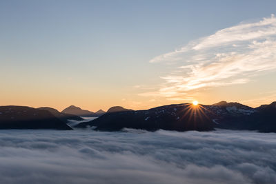 Idyllic shot of mountains in foggy weather during sunset