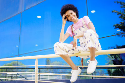 Portrait of young woman standing against clear sky