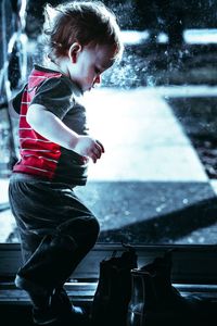 Side view of boy standing by shoes