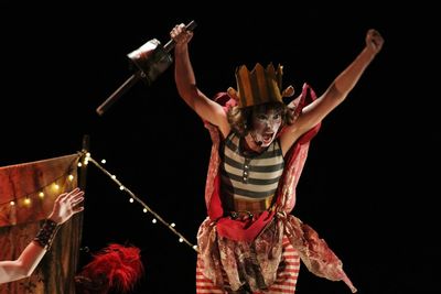 Midsection of woman with arms raised standing against black background