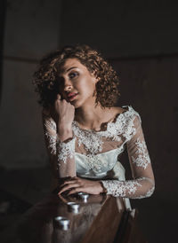 Portrait of beautiful woman in wedding dress leaning on piano at home