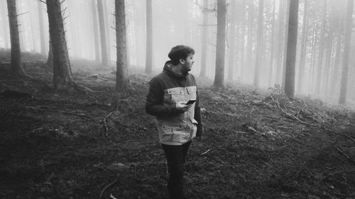 Man using mobile phone in foggy forest