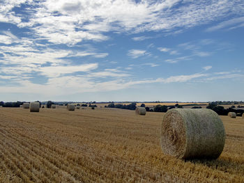 Hay bales on field against sky