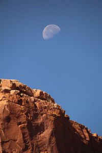 Low angle view of half moon against clear blue sky