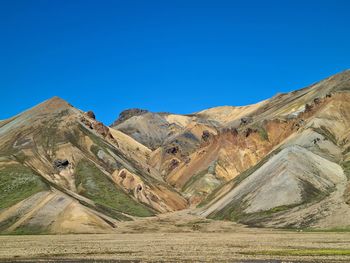 Scenic view of arid landscape against clear blue sky