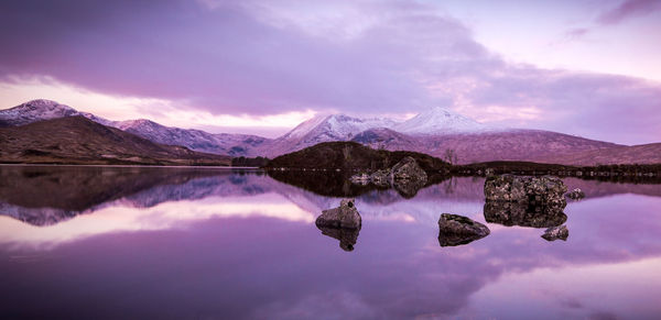 Scenic view of lake and mountains against cloudy sky