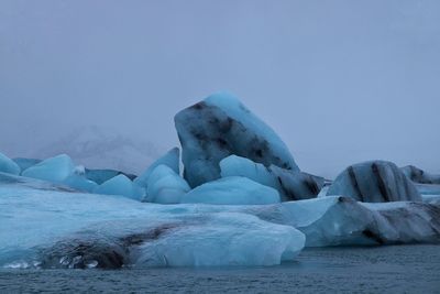 Scenic view of glaciers by sea against sky