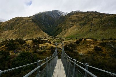 Footbridge over mountain against sky