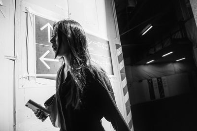 Side view of young woman looking through window