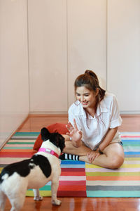 Happy friends sitting on floor against wall