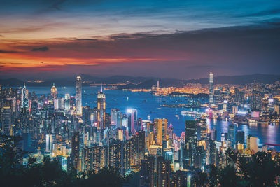 Illuminated modern buildings in city against sky at night