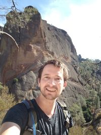 Portrait of smiling young man standing on rock