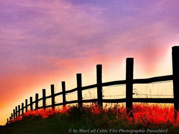 Fence on field against sky during sunset