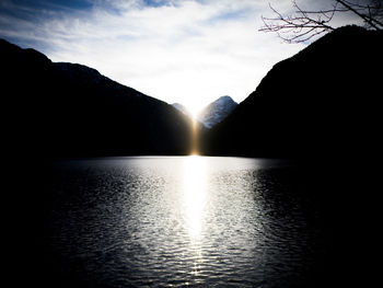 Scenic view of lake by silhouette mountain against sky