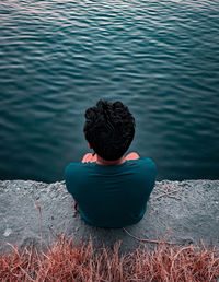 Rear view of man sitting by lake