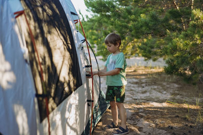 Cute little caucasian boy helping to put up a tent. family camping concept