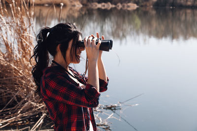 Woman looking at lake through binoculars