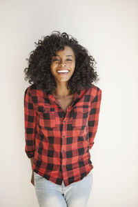 Portrait of smiling young woman standing against white wall