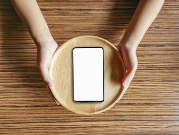 Directly above shot of woman holding smart phone on table