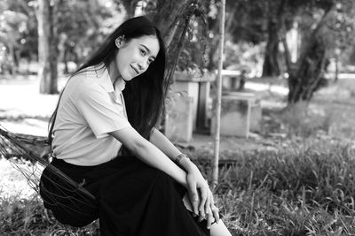 Young woman looking away while sitting on hammock in park