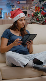 Portrait of woman using laptop while sitting on sofa at home