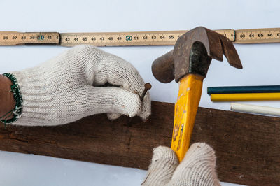 Cropped hands of carpenter hammering on plank