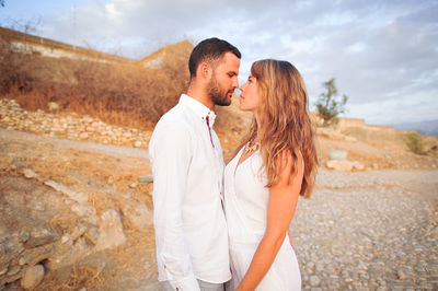 Side view of young couple looking each other face to face while standing on land