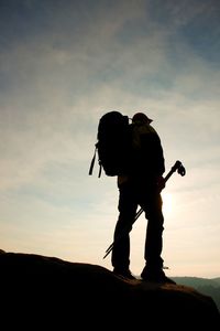 Low angle view of silhouette man standing on mountain against sky