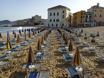 Chairs on beach by buildings against clear sky