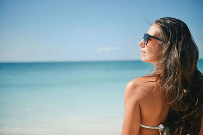 Beautiful woman looking at sea shore against sky