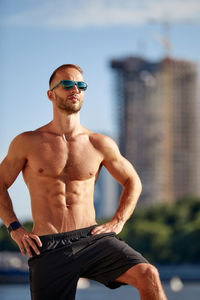 Shirtless young man wearing sunglasses while standing outdoors