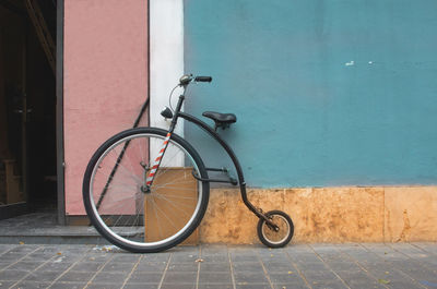 Bicycle parked on wall by footpath against building