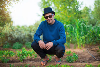 Young man wearing hat sitting on land